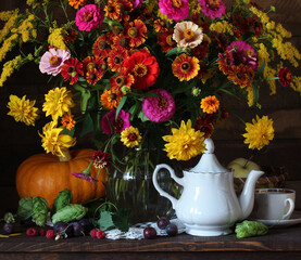Obraz na płótnie Canvas autumn bouquet of plums raspberries pumpkin and tea dishes on the table