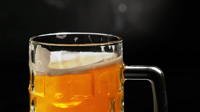 Man hand put beer mug with craft drink on the table and glass standing isolated on dark grey background