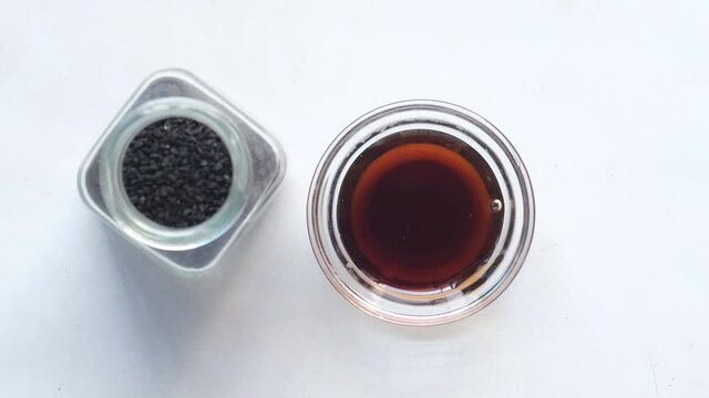 pouring Black Cumin oils in a container on white 