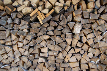 A pile of birch firewood and cut boards for burning, stacked in rows, fuel for the winter