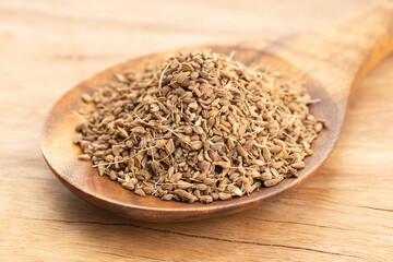 Anise spice seeds in wooden spoon on wooden table. Close up