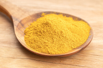 Curry powder in wooden spoon on wooden table. Close up