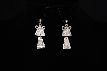 Tribal style of silver earring on black cloth background