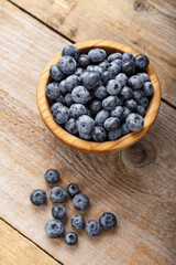 Freshly picked blueberries in a wooden bowl. Healthy food and nutrition concept.
