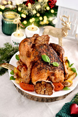 Roasted whole chicken with vegetables and garlic on Christmas table