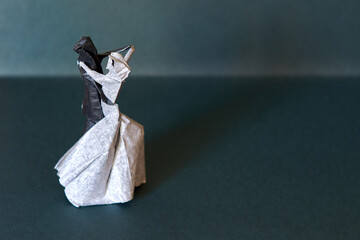 Origami dancing couple figure on a bluish green backgrund. Romantic and beautiful origami bride and...