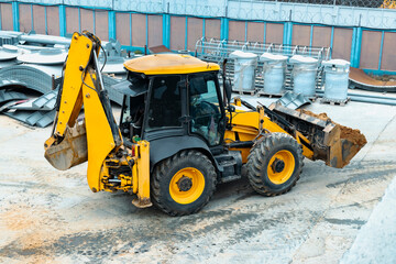 A multipurpose excavator with a front bucket transports soil to the construction site. View from above. Construction machinery for earthworks.