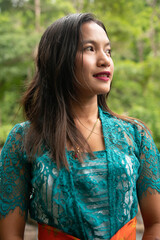 Portrait of a beautiful asian girl by the river in a brightly colored suit and offerings in hand. 