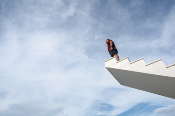 Asian fat man stand on wooden stairway with blue sky background.