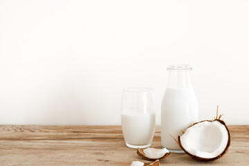 Fototapeta na wymiar Fresh coconut milk in glass bottle, vegan non dairy healthy drink. Wooden table, close-up. Free space for text, copy space.