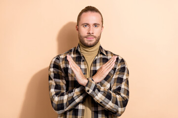 Photo of young man crossed hands demonstrate stop symbol protest isolated over beige color...