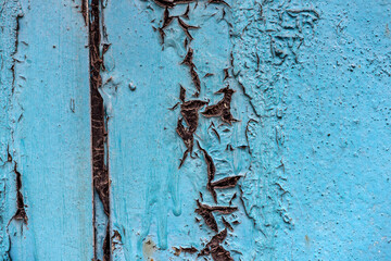 Peeling paint on the wall. Old wall with cracked flaking paint. Weathered rough painted surface with patterns of cracks and peeling. Grunge texture for background and design. High resolution.