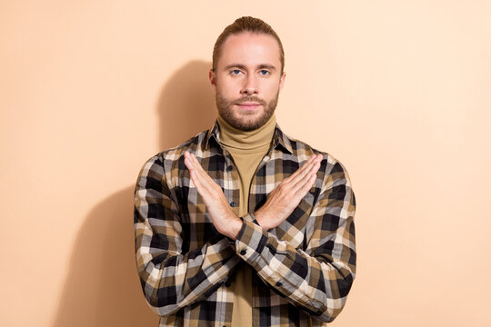Photo of young man crossed hands demonstrate stop symbol protest isolated over beige color background