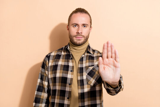 Photo of young handsome guy show arm stop ban denial symbol reject isolated over beige color background