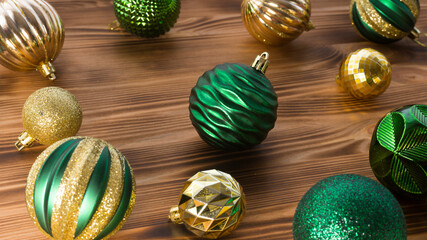 Christmas balls of green and gold color on a wooden surface