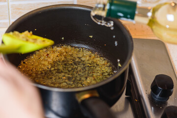 frying onions with spices on a gas stove in a round tall pan. Top view 