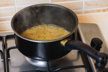frying onions with spices on a gas stove in a round tall pan. Top view 