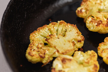 Vegetarian food. Grilled cauliflower steak on a cast iron skillet, top view, close-up view.