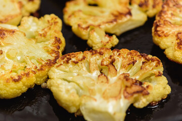 Vegetarian food. Grilled cauliflower steak on a cast iron skillet, top view, close-up view.