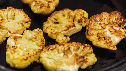 Vegetarian food. Grilled cauliflower steak on a cast iron skillet, top view, close-up view.