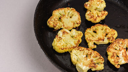 Vegetarian food. Grilled cauliflower steak on a cast iron skillet, top view, close-up view.