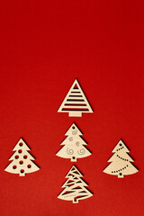 Fototapeta premium Christmas red background, with wooden Christmas trees. Minimalistic Christmas red background. Christmas background with toys top view on a red background. New Year card.