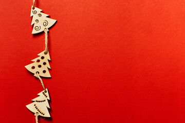 Christmas red background, with wooden Christmas trees. Minimalistic Christmas red background. Christmas background with toys top view on a red background. New Year card.