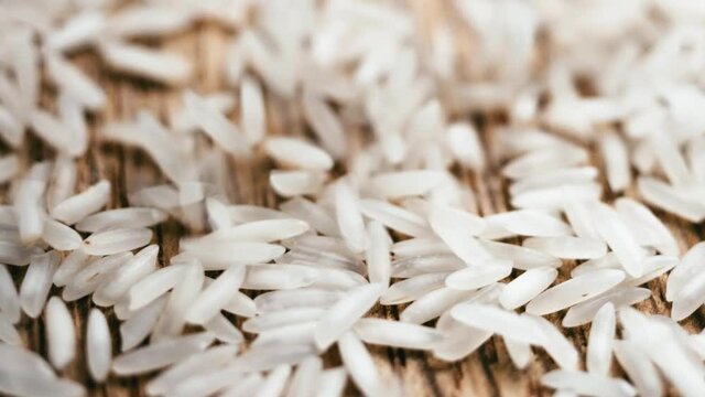 White long rice poured from the top on the wooden textured table. Healthy dry grains of chinese national food. Organic uncooked vegeterian ingridient for risotto