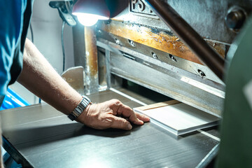 Crop senior worker operating large printing machine