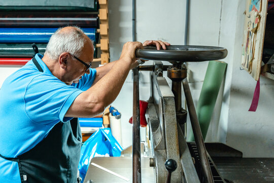 Concentrated senior man operating machine in printing studio