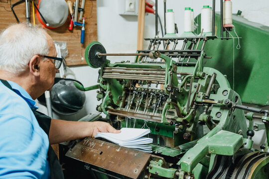 Crop male artisan operating paper cutting machine in workshop