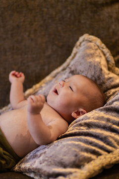 Sad infant screaming while lying on couch at home