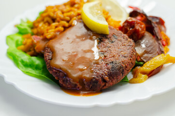 Meat free burger and long grain rice with red peppers, tomatoes and jalapeno chillies