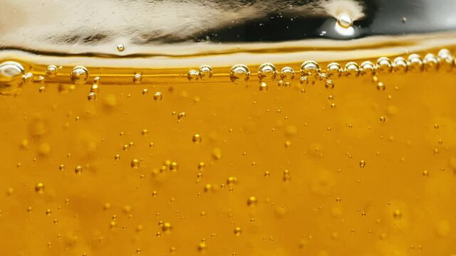 Natural golden olive oil with bubbles in glass bowl. Organic raw liquid closeup. Healthy ingredient for cooking