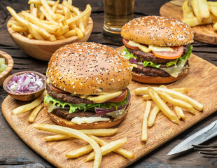 Hamburgers and French fries on the wooden tray.