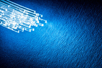 Bundle of optical fibers with lights in the ends. Blue background.