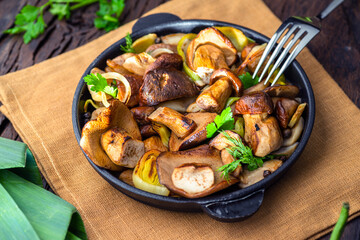 Cooked porcini mushrooms in the frying pan on the wooden table. Top view.