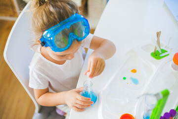 Science. Little cute girl sets up experiments at home, colored liquids, laboratory child's installation.
