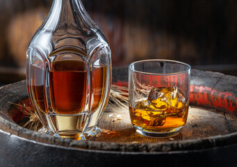 Carafe of whisky and glass of whisky on old wooden cask at the dark background.