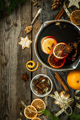 Top view ingredients for Swedish glögg on wooden background. Traditional Nordic drink. Mulled wine with spices, orange and raisins.