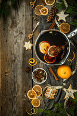 Top view ingredients for Swedish glögg on wooden background. Traditional Nordic drink. Mulled wine with spices, orange and raisins.