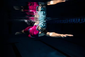 Fototapete Bestsellern Sport Eine Schwimmerin mit Badekappe und Schutzbrille beim Training im Pool, drinnen. Unterwasseransicht der Details der Schwimmbewegungen.