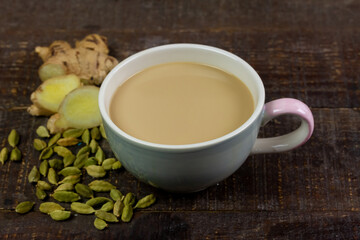 Cup of Masala chai tea with ginger and cardamom on rustic wooden background. Masala chai popular traditional India hot drink made of milk, tea and spices.