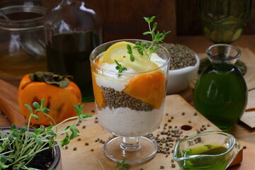 Dessert with yogurt, persimmon and hemp sativa sprouts on wooden background