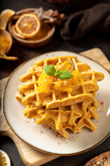 Homemade pumpkin waffles with walnuts in a plate on a culinary background close-up	