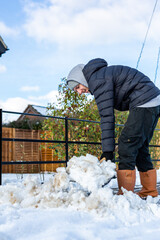 A young man clearing the footpath of snow and ice to make it safe to walk on during a heavy snowfall. Winter safety, clearing snow and ice concept