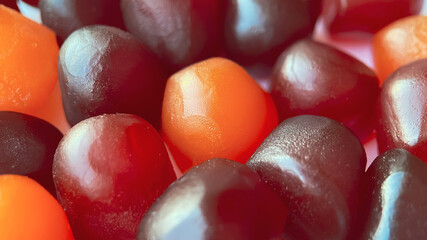 Close-up texture of red, orange and purple multivitamin gummies on white background. Healthy...