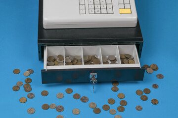 An open cash register and scattered coins on a blue background.
