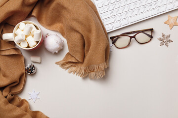Winter desk work. Beige cashmere scarf keyboard glasses marshmallow with Christmas decorations on a...