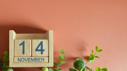 November 14, Date design with calendar cube and leaf on orange background.